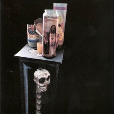 A skull with a candle and a jar on a table

Description automatically generated