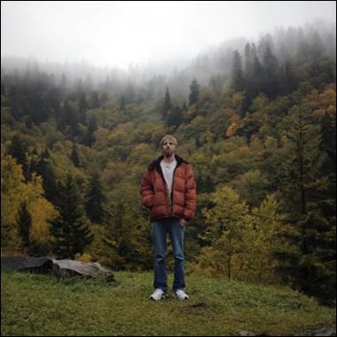 A person standing on a hill with trees in the background

Description automatically generated