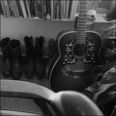A guitar and boots on a shelf

Description automatically generated