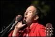 A person in a red shirt singing into a microphone

Description automatically generated