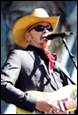 A person in a cowboy hat and sunglasses singing into a microphone

Description automatically generated with medium confidence