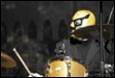 A person wearing a yellow mask and holding a drum

Description automatically generated with medium confidence