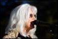 A person with white hair and sunglasses singing into a microphone

Description automatically generated with medium confidence