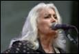 A person with white hair singing into a microphone

Description automatically generated