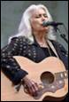 A person with white hair playing guitar

Description automatically generated
