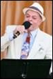 A person in a white suit and hat singing into a microphone

Description automatically generated with medium confidence