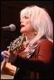 A person with white hair and a guitar

Description automatically generated