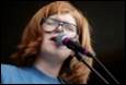 A person with red hair singing into a microphone

Description automatically generated