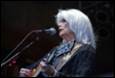 A person with white hair playing a guitar

Description automatically generated