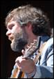 A person with a beard and a guitar

Description automatically generated