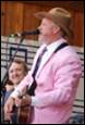 A person in a pink suit singing into a microphone

Description automatically generated