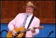 A person in a pink suit playing a guitar

Description automatically generated