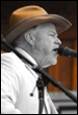 A person in a cowboy hat singing into a microphone

Description automatically generated