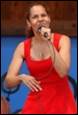A person in a red dress holding a microphone

Description automatically generated
