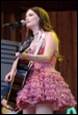A person in a pink dress playing a guitar

Description automatically generated