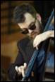 A person with a beard and sunglasses playing a cello

Description automatically generated