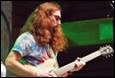 A person with long red hair playing a guitar

Description automatically generated