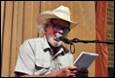 A person in a cowboy hat speaking into a microphone

Description automatically generated