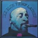 A person smoking a cigar on a blue cover

Description automatically generated