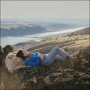 A person lying on a rock with a blanket on her back

AI-generated content may be incorrect.