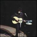 A person playing a guitar on a stage

Description automatically generated