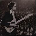 A person holding a guitar in front of a crowd

Description automatically generated