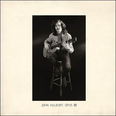 A person sitting on a stool playing a guitar

Description automatically generated