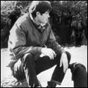 A person sitting on a rock with a dog

Description automatically generated