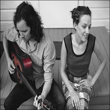 A person and person sitting on stairs playing guitar
Description automatically generated