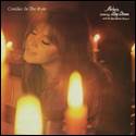 A person with her eyes closed and a guitar in front of candles

Description automatically generated