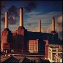A large factory with smoke stacks with Battersea Power Station in the background

Description automatically generated