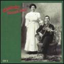 A person and person in white dress and a person in white dress sitting in a chair with a violin

Description automatically generated