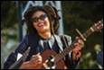 A person with dreadlocks playing a guitar

Description automatically generated