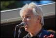 A person with white hair speaking into a microphone

Description automatically generated with medium confidence