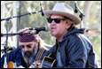 A person in a cowboy hat and sunglasses playing guitar

Description automatically generated with low confidence