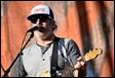 A person playing guitar and singing into a microphone

Description automatically generated with medium confidence