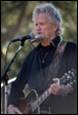 A person playing guitar and singing into a microphone

Description automatically generated with medium confidence