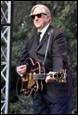 A person in a suit and tie holding a guitar

Description automatically generated with medium confidence