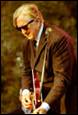 A person in a suit and tie playing a guitar

Description automatically generated with medium confidence