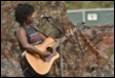 A person playing guitar on stage

Description automatically generated