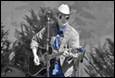 A person playing guitar and wearing a cowboy hat

Description automatically generated