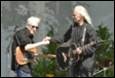 A person holding a guitar and another person holding a guitar

Description automatically generated