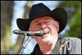 A person in a cowboy hat singing into a microphone

Description automatically generated