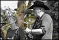 A person in a cowboy hat holding a violin

Description automatically generated