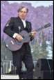 A person in a suit playing a guitar

Description automatically generated