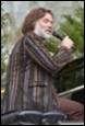 A person with a beard speaking into a microphone

Description automatically generated
