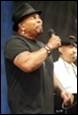 A person wearing a hat and holding a microphone

Description automatically generated with medium confidence