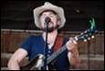 A person in a cowboy hat playing guitar

Description automatically generated with medium confidence