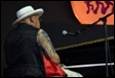 A person in a white hat sitting on a piano

Description automatically generated with low confidence