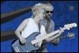 A person playing a guitar with a person in the background

Description automatically generated with low confidence